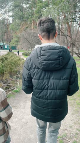 boys are walking along the path in the park, two friends are walking together