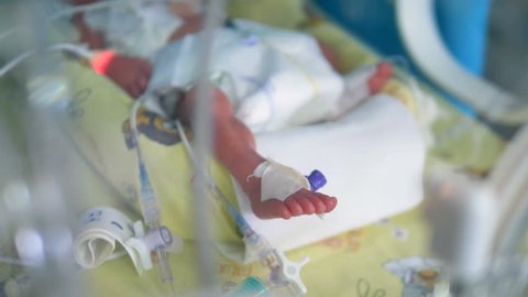 A newborn baby lying inside a crib at a hospital. 