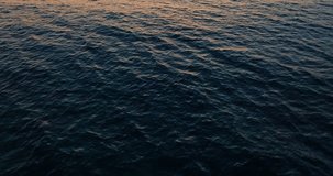 Aerial view of the sunset in the seascape. Beautiful waves of the ocean in the rays of the red sun. High quality 4k footage