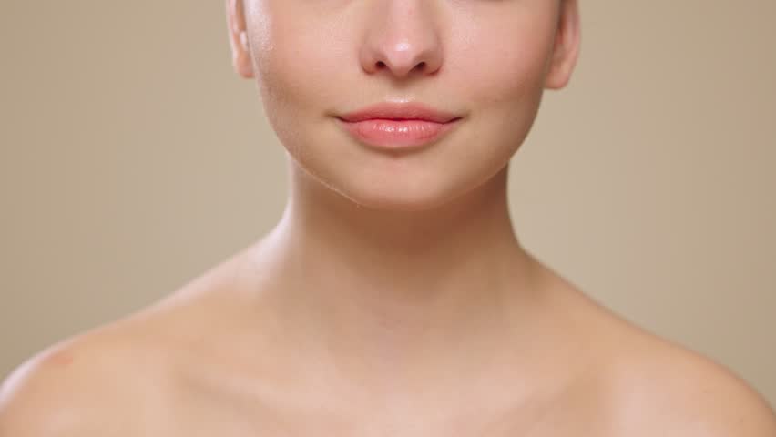 Beautiful Young Woman Touches Her Perfect Face. Natural Cosmetic Skincare Products. Woman demonstrate moisturizing facial care. Elevating Close-up Portrait with Isolated Background. Slow motion