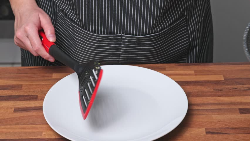 Chef fries eggs with broccoli, bacon and spinach. A woman putting scrambled eggs on a plate.