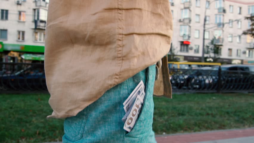 dollar bills sticking out of the pocket of a man.