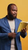 Vertical video African american orator reading book aloud, narrating story for audience. BIPOC person presenting literature novel, reciting from pages, entertaining spectators, studio background