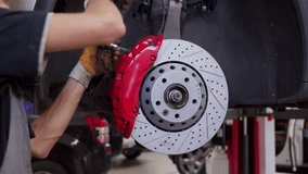 Auto mechanic replaces brake disc on car at repair shop. Hands use tools to install new pads, caliper on wheel hub. Vehicle maintenance footage for instructional, commercial, DIY project use. - Powered by Shutterstock - Get 15% off with code: PIKWIZARD15
