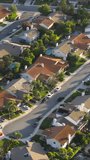 Vertical video. Los Angeles suburban housing district area in USA. Aerial drone shot of residential American homes in quiet neighborhood at golden hour. Beautiful green suburb aerial at scenic sunset - Powered by Shutterstock - Get 15% off with code: PIKWIZARD15