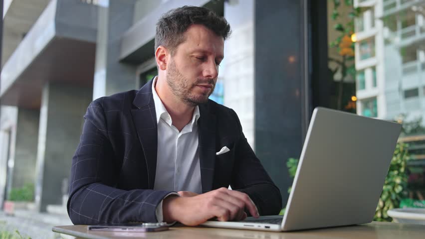 Handsome 30s top manager work laptop. Entrepreneur type computer macbook. Business man look monitor. Young male businessman. Urban city background. 40s employee create start up. Ceo office boss job.