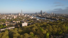Aerial View Shot of London, UK, during the day, Shard and Tower Bridge, the City of London skyline, lush greenery along the River Thames, capturing the essence of summer and spring