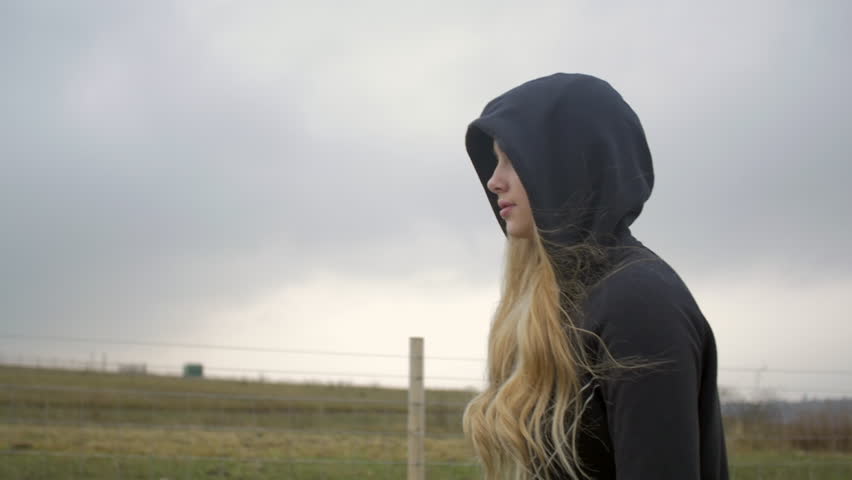 Slow motion - Young blonde girl with hood up staring and walking fiercely  | Shutterstock HD Video #34890073