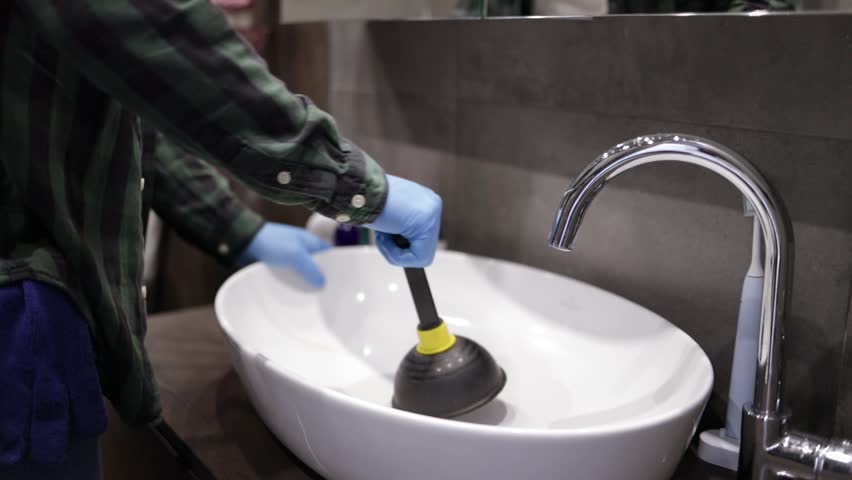 plunger unblocking white wash hand basin sink, man's hand. Royalty-Free Stock Footage #3489096425