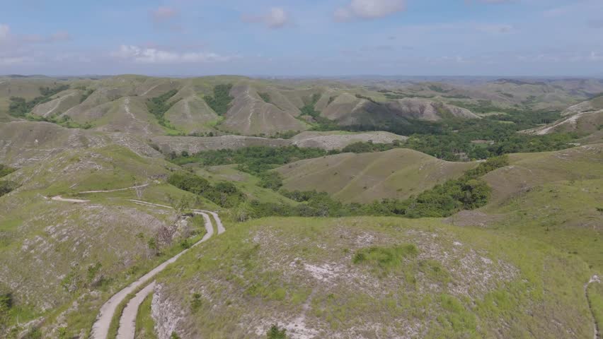 A beautiful landscape with a winding road that leads to a valley. The sky is clear and the sun is shining, creating a peaceful and serene atmosphere.