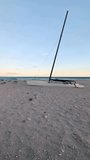 Alone sailing catamaran stands on the beach. Storing sailboat in the open air during out-of-season. Slow motion video.