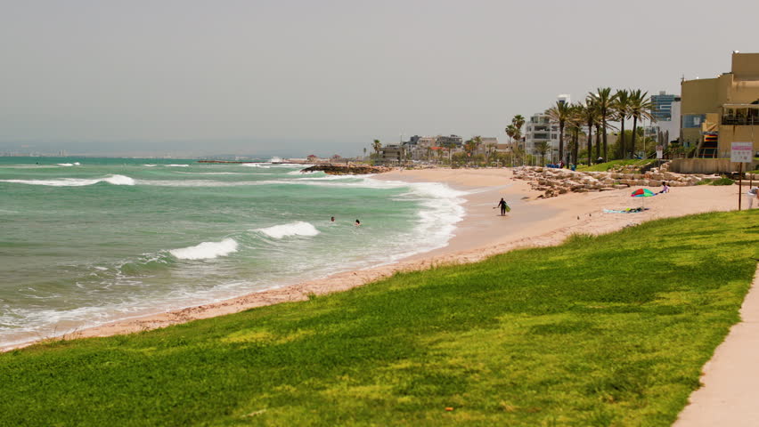 Sandy beach in Haifa, Israel. with a stunning beach, turquoise water and surfers.