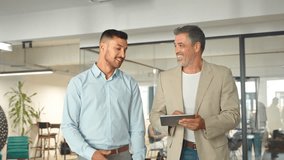 Two busy happy executive business team of two men walking in office and talking. Busy professional managers working together using digital tablet computer tech going in corporate office hallway. - Powered by Shutterstock - Get 15% off with code: PIKWIZARD15