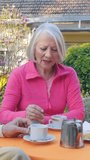 A couple of elderly people enjoying outdoor time at the table. Vertical Video