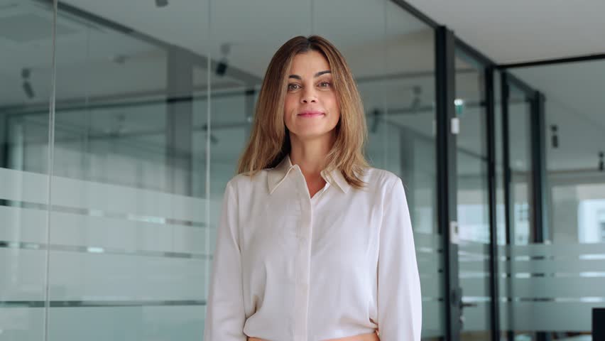 Happy 45 years old Latin professional middle aged business woman corporate leader, smiling mature female executive manager standing in office looking at camera arms crossed, portrait.