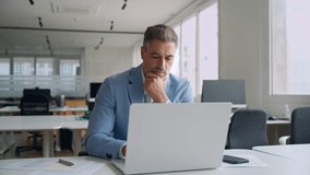 Busy middle aged professional business man ceo, 50 years old businessman executive wearing blue suit using laptop computer thinking on financial investment working in corporate office. Authentic video - Powered by Shutterstock - Get 15% off with code: PIKWIZARD15