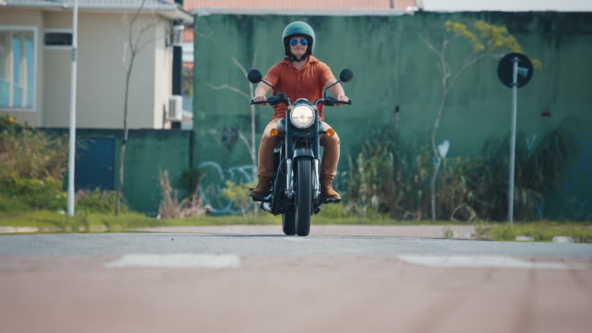 Man rides black motorcycle on the street in Brazil. Front side view of the rider on classic motorcycle approaching the camera
