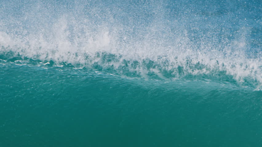Ocean wave breaks on the shore in Brazil. Breaking wave close up. Camera pans and follows the breaking lip of the wave