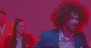 Young funny man wearing bright suit and wig dancing with a group of people dancers together enjoying disco party and having fun in neon lights in night club. 4k video. Slow motion video.