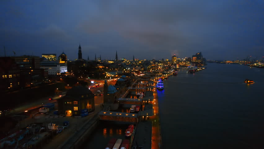 Aerial drone view of Hamburg at evening, Germany. Elbe coastline, moored boats, sea port, classic and modern buildings, roads with cars and nightlights