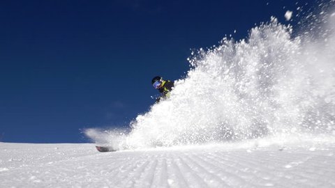 Slow motion - Low angle view of alpine skier spraying snow into camera