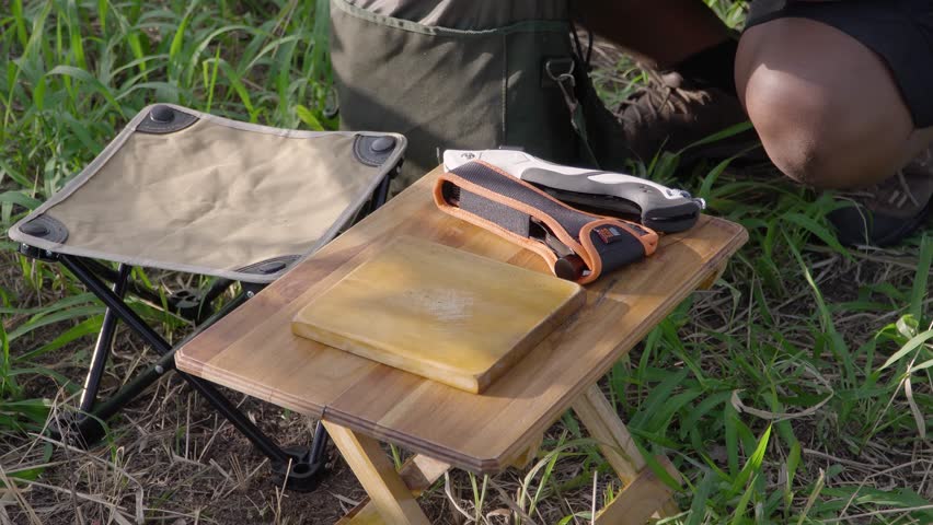 Outdoor camping concept: men prepare cooking equipment and chop wood with ax and start a fire. Survival activities consist of cooking in the forest with minimal equipment