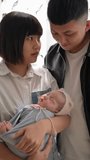 Vertical video of a Taiwanese mother and father in their 20s standing in front of the curtain with a baby girl who is 1 month old