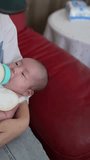 
Vertical video of a Taiwanese mother in her 20s changing a 1-month-old girl's baby on a red sofa