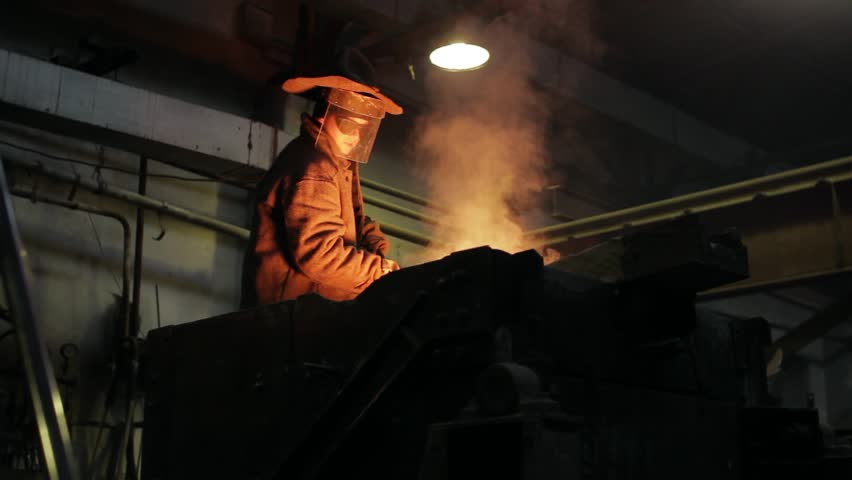 Azov Shipyard. Industrial worker in protective gear oversees molten metal pouring furnace at steel mill. Foundry professional in heat-resistant suit controls smelting process, crucial for