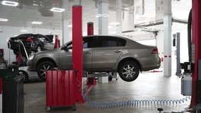 Vehicle suspended on hoist in auto repair shop for maintenance. Mechanic inspects car on lift, fixing undercarriage. Professional garage, tech work, service station with elevated sedan. - Powered by Shutterstock - Get 15% off with code: PIKWIZARD15