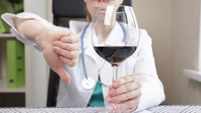 doctor refuses alcohol, shows thumbs down to glass of wine, no alcoholic drinks, boozing refusal, health care