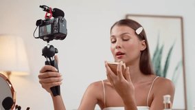 Young woman making beauty and cosmetic tutorial video content for social media. Beauty blogger smiles to camera while showing how to beauty care to audience or followers. Adit