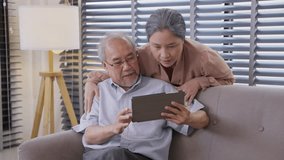 Asian grandparents watching on digital table or video call with family. Senior couple talking together and using internet browsing online at home
