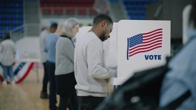 Elderly male voter with bulletin in hands comes to voting booth. Multicultural American citizens come to vote in polling station. Political races of US presidential candidates. National Election Day. - Powered by Shutterstock - Get 15% off with code: PIKWIZARD15