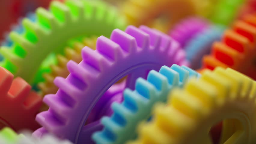 Looping 3D animation of a group of multi-colored plastic toy gears. Close-up. Defocus