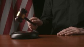Male sitting at the desk with wooden hammer and law book, USA flag at the background. Man judge in the court room, hitting wooden gavel, close up shot. - Powered by Shutterstock - Get 15% off with code: PIKWIZARD15
