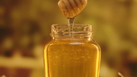 Opened glass jar standing on the table with fresh golden honey, hand dipping honey dipper in the jar with thick syrup, close up shot. - Powered by Shutterstock - Get 15% off with code: PIKWIZARD15