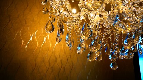 slow moving of Brilliant crystal chandelier hanging on ceiling with filter color effect  in a luxurious interior