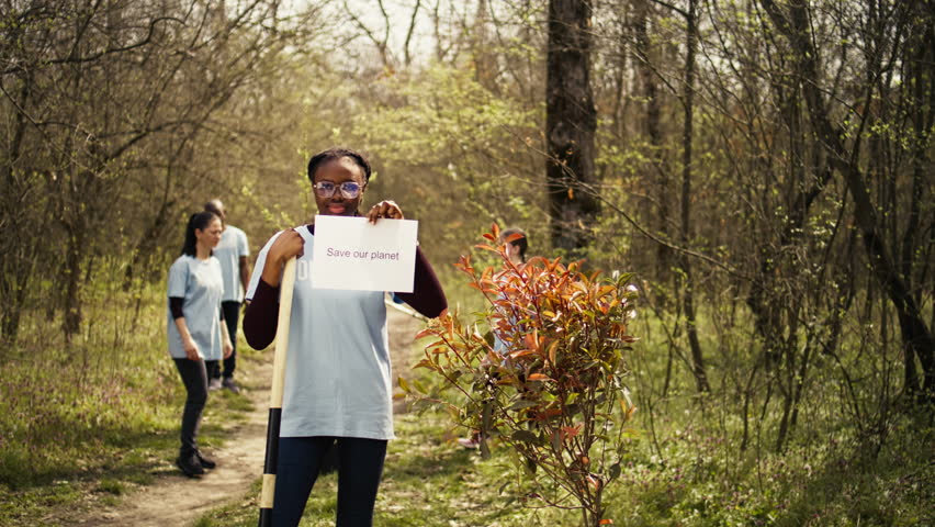 Portrait of african american activist holding poster with save our planet message, spread environmental care and awareness. Young woman posing with banner to fight ecological justice. Camera B. Royalty-Free Stock Footage #3490203487