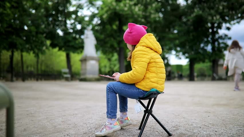 Young preschooler painter drawing outdoor scene with fusain in Luxembourg garden of Paris, France.