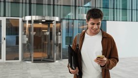 Young man walking while using cell phone. Happy university student smiling in the city - Powered by Shutterstock - Get 15% off with code: PIKWIZARD15