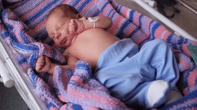 Close-up portrait of a newborn baby in the hospital with tags on the handles in the crib.  - Powered by Shutterstock - Get 15% off with code: PIKWIZARD15