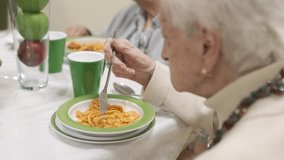 Senior woman eating pasta in nursing home canteen