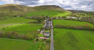 Aerial video of a straight road leading up to the hills with wind turbines in Edenfield, Bury, Greater Manchester.