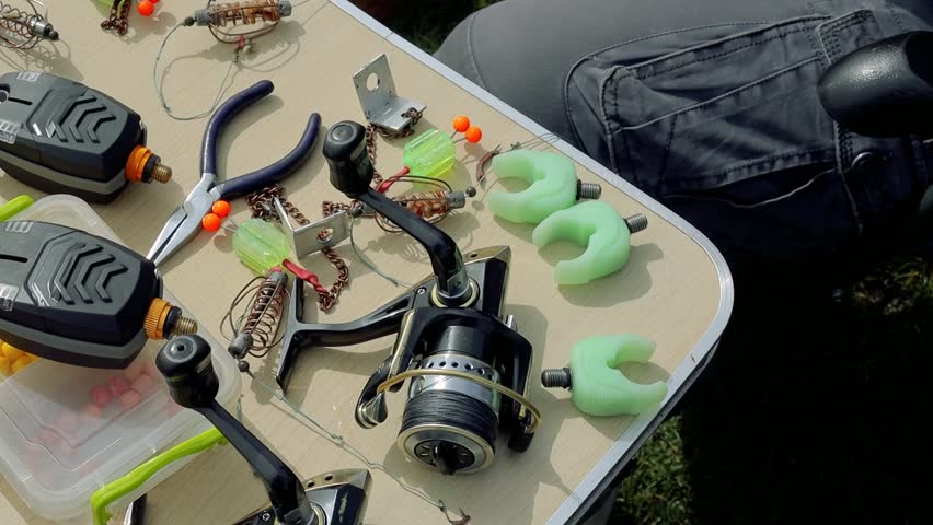 Mature adult senior angler fisherman cleaning fishing rod setup with multiple rods on a stand with alarms set lines near lakeside in early morning. Angling equipment gear. Fishing reels tackle holders Royalty-Free Stock Footage #3490611307