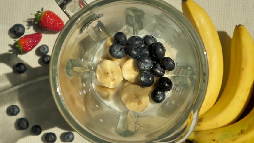 Grind the Top View berry milkshake in a blender and beat with the addition of blueberries and banana pieces. Prepare a berry-fruit smoothie using a blender. Slow motion cooking smoothie