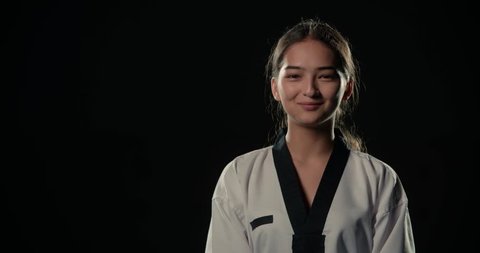 asian beautiful girl fighter taekwondo portrait with smile, dressed in kimono, black background,