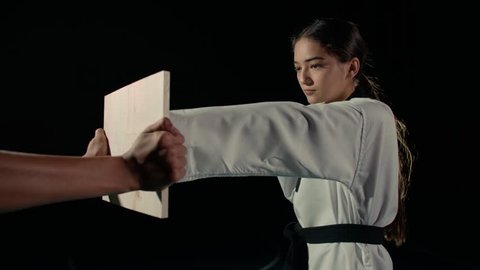 Asian beautiful girl fighter practicing to break the board with a blow of the hand, slow motion