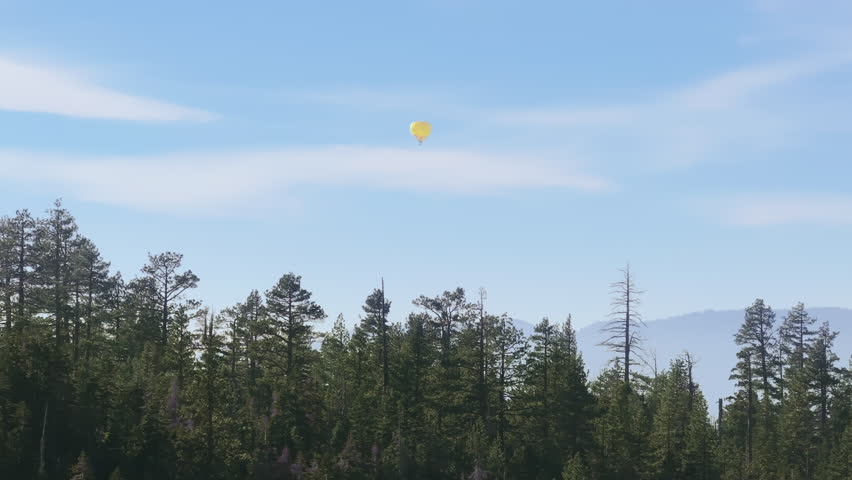 A tranquil hot air balloon floats above Lake Tahoe, surrounded by the calm of the forest and the early morning sky. 4K footage.
