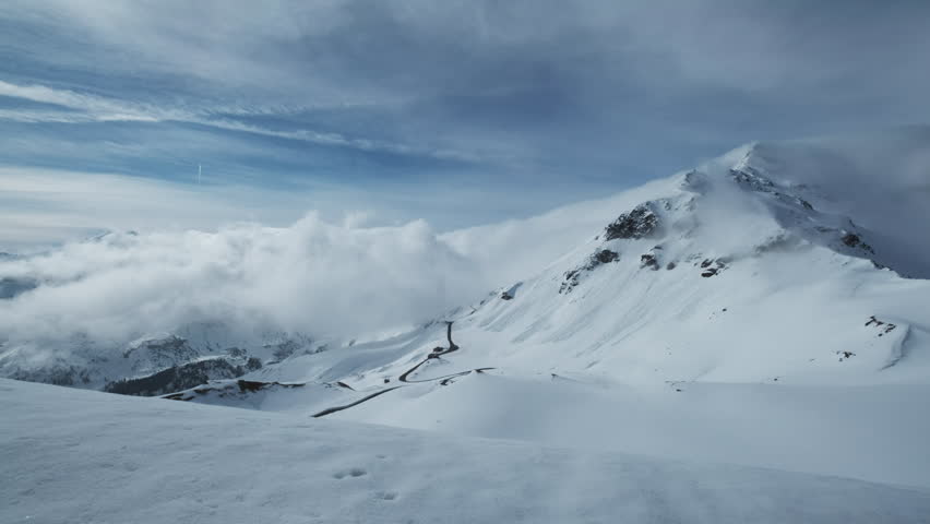 Grossgloknershtrasse in snow and clouds. Great high mountain road near Grossglokner mount in Austrian Alps, 4k